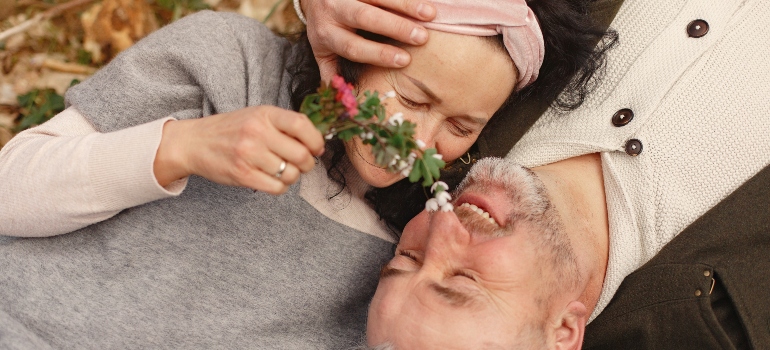 an elderly couple laying on a bed of leaves