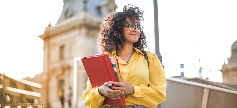 A student holding books, happy after moving from Orangeville to East York