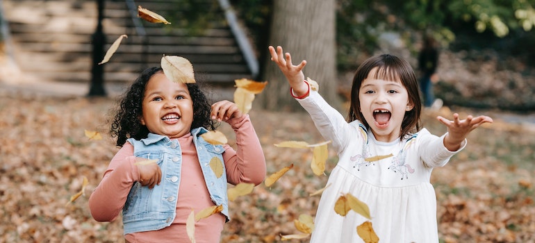 Two little girls playing in the leaves
