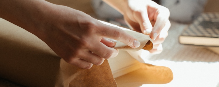 Person packing a book in paper