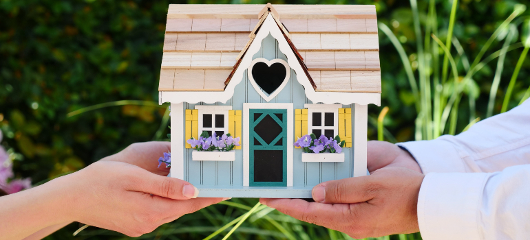 Two people holding a miniature house