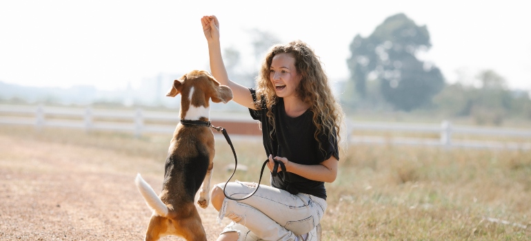 A woman playing with her dog knows how to make cross border relocation easier on your pet.