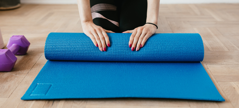 Person rolling up a yoga mat in order to store gym equipment properly