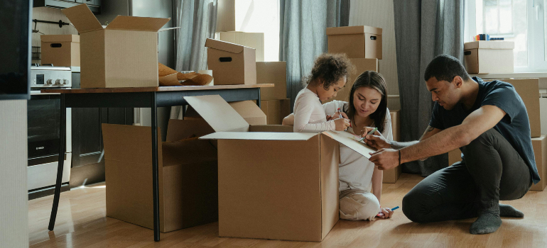 A family of three engaged in unpacking boxes.