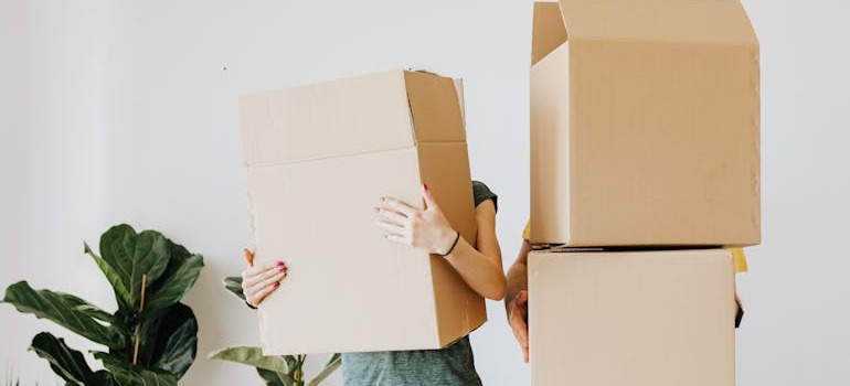 A couple holding cardboard moving boxes