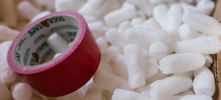 Red packing tape and packing peanuts in a moving box