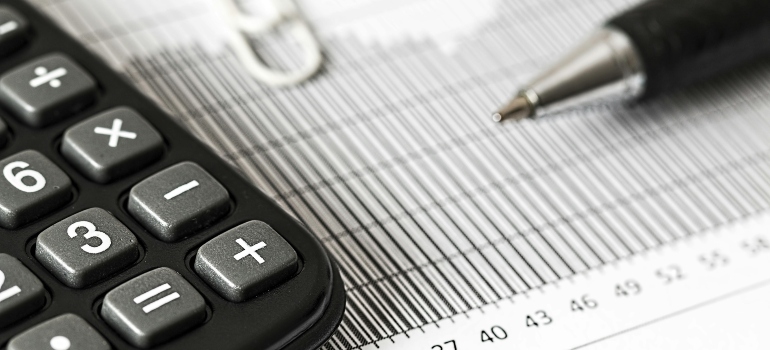 Calculator and Pen on Table helping you analyze the mistakes to avoid when moving from Canada to USA