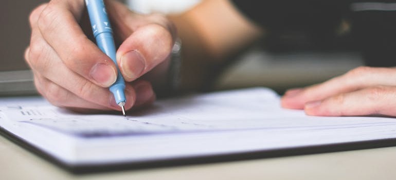 A person writing a list about how to avoid common moving scams when moving to Guelph