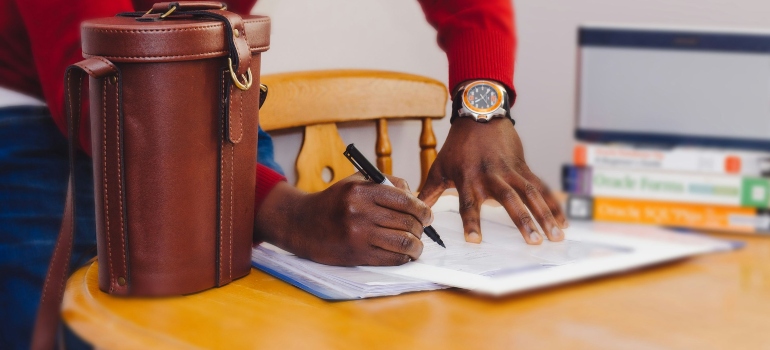 Picture of a person signing a contract after weighting out the pros and cons of moving to Ajax