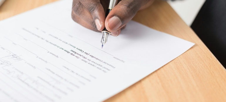 a person signing a home contract after reading a guide to living in Surrey