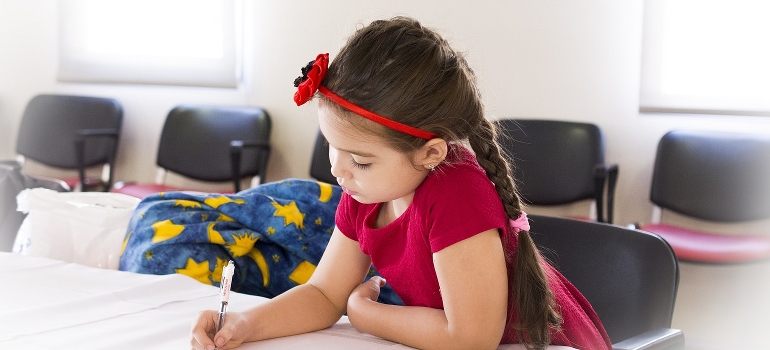 A little girl writing in school after moving your family from Richmond Hill to Thornhill.