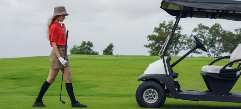Woman on a golf court walking towards a golf cart