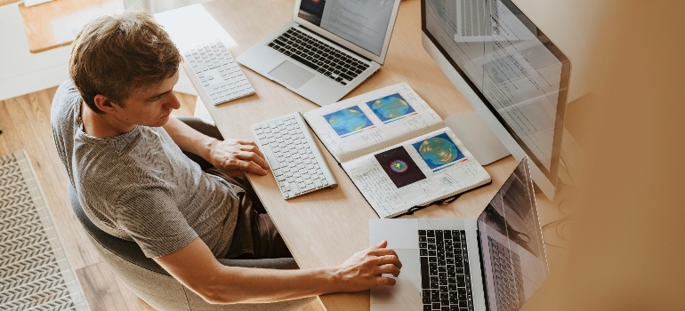 Man Using 3 Computers And Researching Toronto's condo move-in and move-out regulations