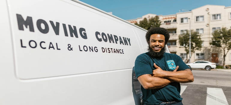 Man in Blue T-shirt and Black Pants Standing Beside White Van