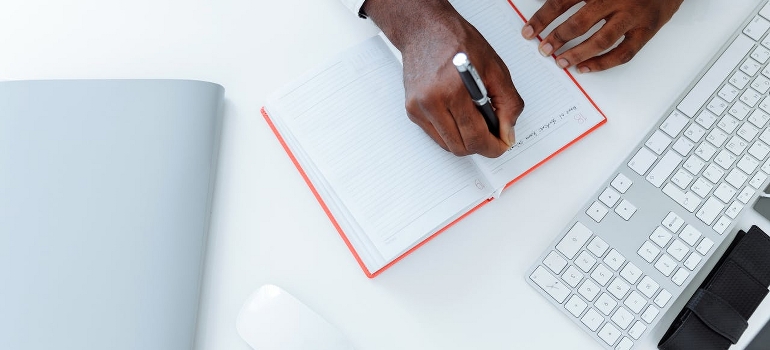 A professional writes notes at the office desk while thinking of what is making so many Canadians leave Canada
