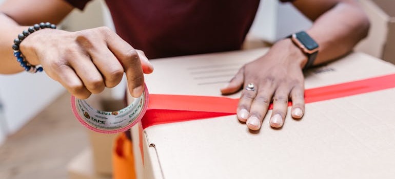 A man closing a box after hiring a moving & storage agency