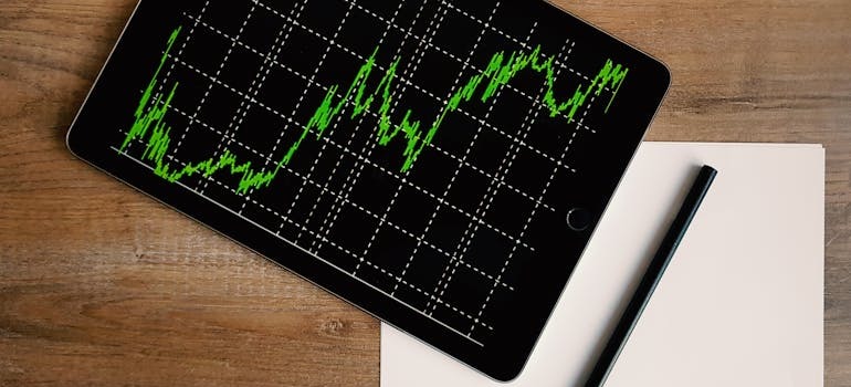 A graph on a smart device with pen and paper beside it