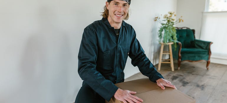 a man in a green working suit holding hands on cardboard box