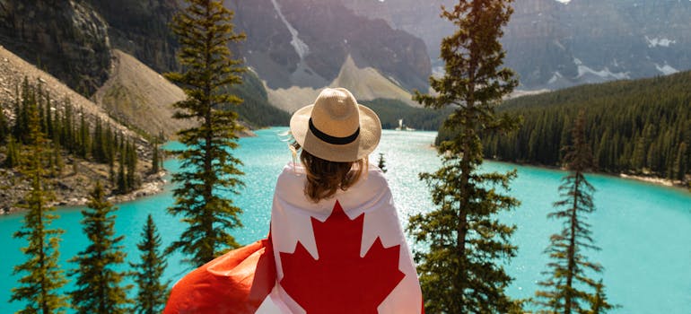 a woman covered with Canadian flag in front of the lake