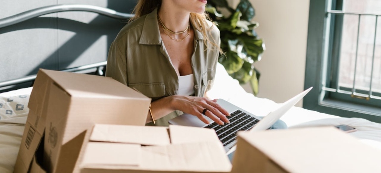 a girl sitting between boxes and working on a laptop
