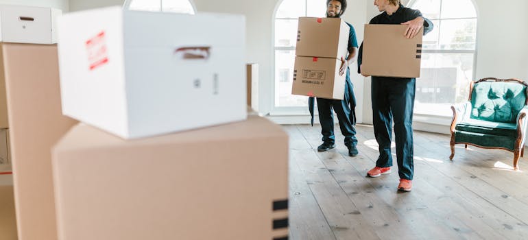 two men in working suits holding boxes in the middle of the room