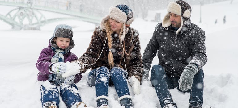 a family of three sitting on the snow
