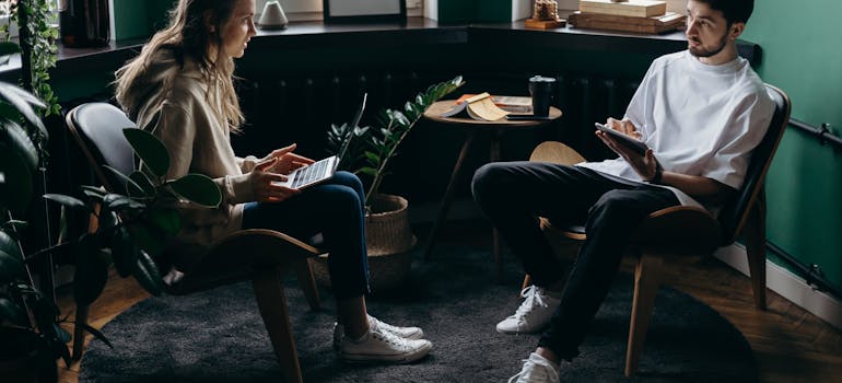 a man and a woman sitting and reading on a laptop about choosing between movers and brokers In Canada