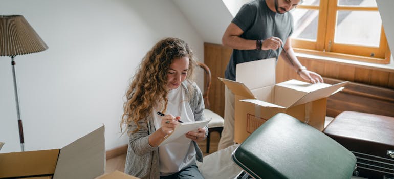 a woman writing on a piece of paper while a man is standing