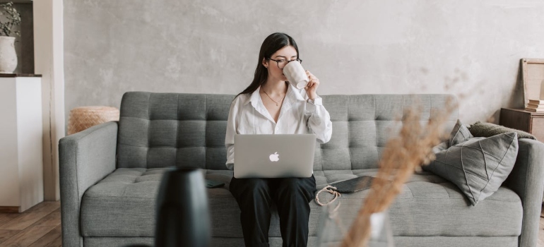 a woman sitting and holding a laptop and reading about the emotional benefits of moving