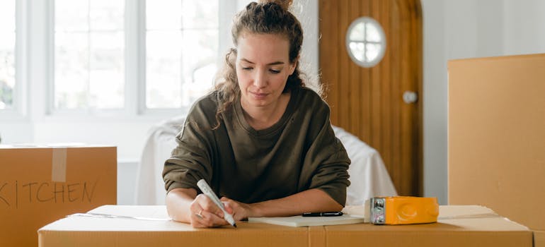 a woman writing on a cardboard box