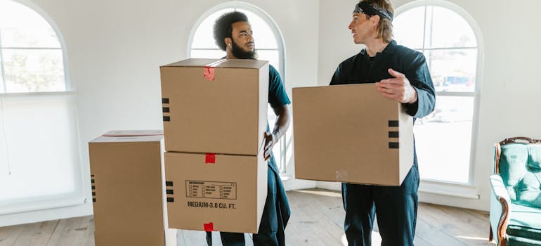 two men in a room holding cardboard boxes