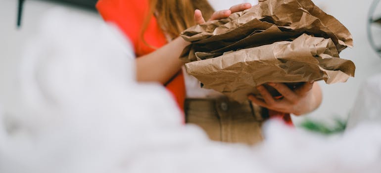 a woman holding packing paper to reduce your environmental footprint during your move from Toronto