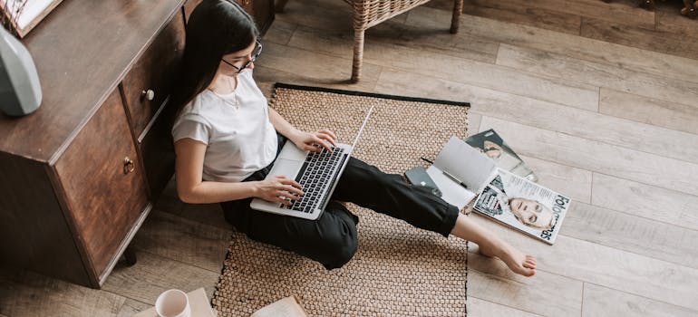 a woman sitting on the floor and reading on a laptop about embracing AI in the moving industry