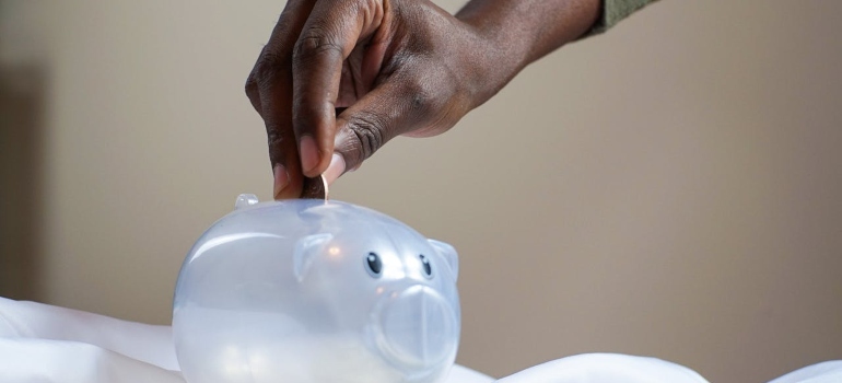 Person putting a coin in a piggy bank