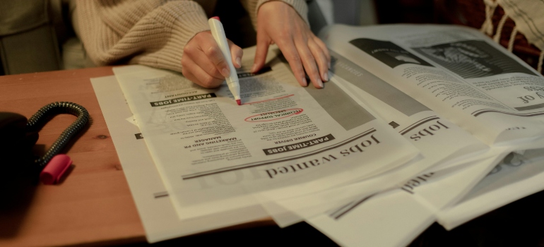 A person highlighting job listings in a newspaper, a key step for job seekers moving to Alberta from Ontario.