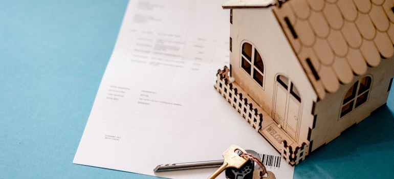 A wooden home and keys on a rental agreement