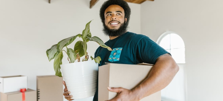 A man holding a box and a plant