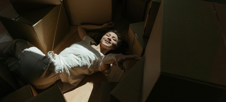 A woman smiling while lying on the floor surrounded by moving boxes—an honest look at what most moving companies won’t tell you.