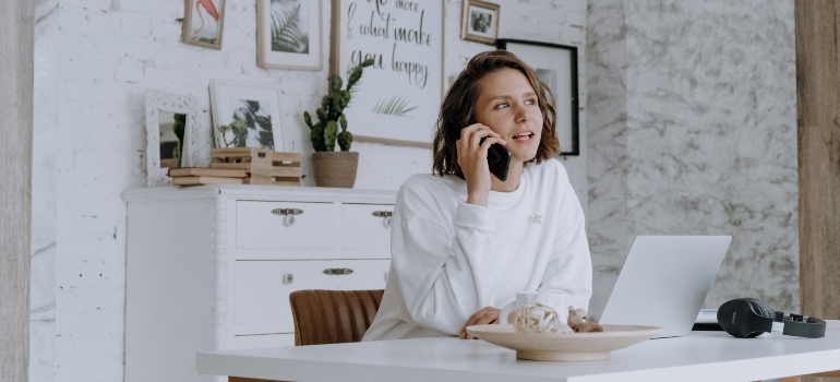 Young woman on the phone working from home during a move—capturing the real side of relocation planning.