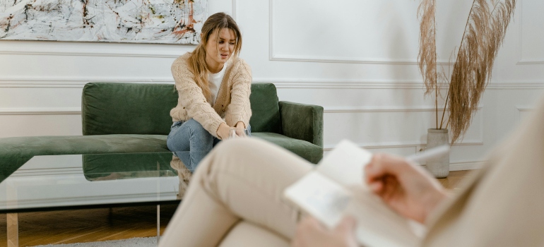 Counselor listening as young woman shares feelings in therapy session.