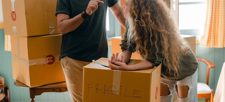 Couple packing labeled moving boxes, preparing for relocation. Prep your home for Toronto movers with organized and secure packing.