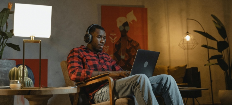 A man in headphones working on a laptop at night, embracing the freedom of remote work.