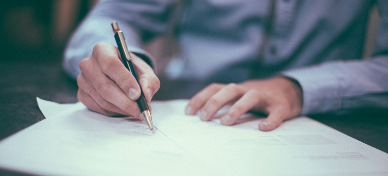 Person signing a contract after moving to Alberta