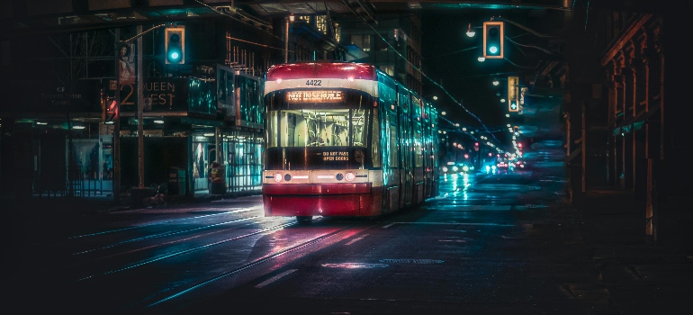 a red streetcar moving on the road during night time