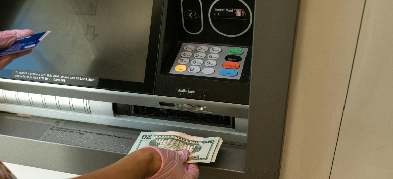 Person deposits money at an ATM, highlighting everyday banking differences between Canada and the US, including account access and services.
