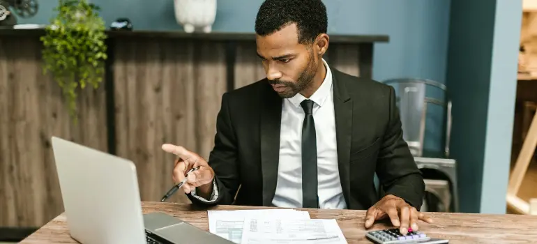 A man in a suit and tie sits at a computer.
