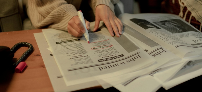 Close up on woman's hand while searching for job postings in newspaper