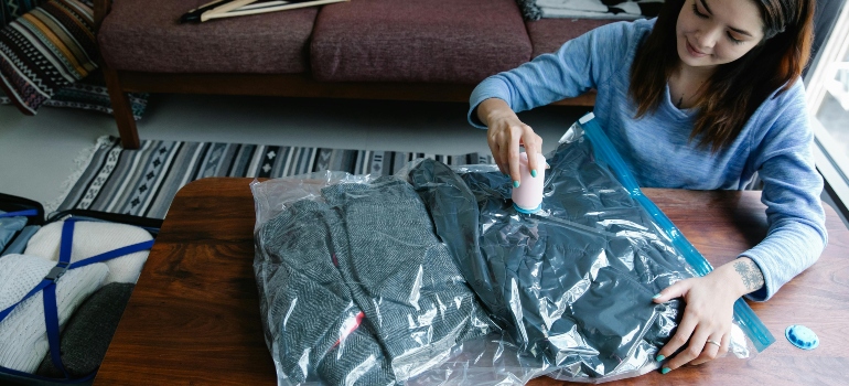 A Woman Vacuum Packing Clothes on a Table before her Move from Etobicoke to Milton