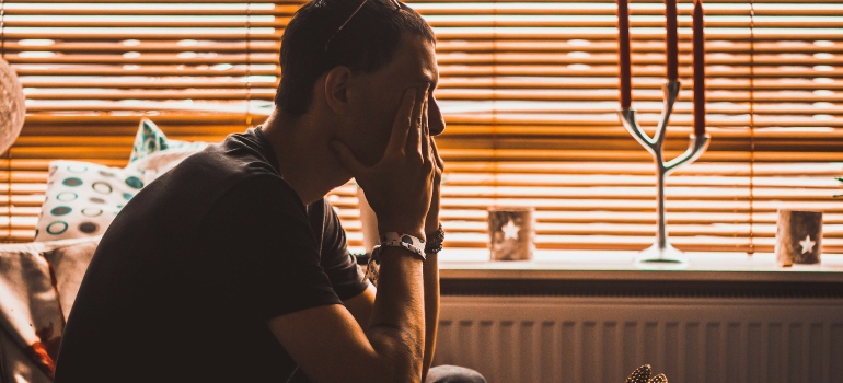 Person covering their eyes while trying to figure out how to relocate without any money