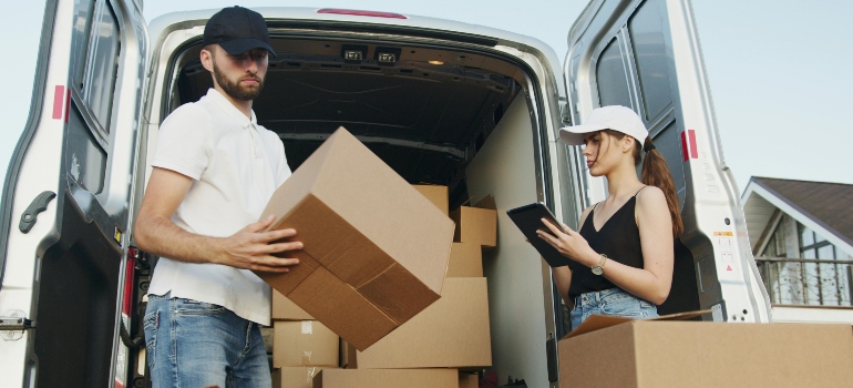 Two people are packing boxes for moving to Calgary, talking about adjusting to life in Mississauga after moving from Calgary.